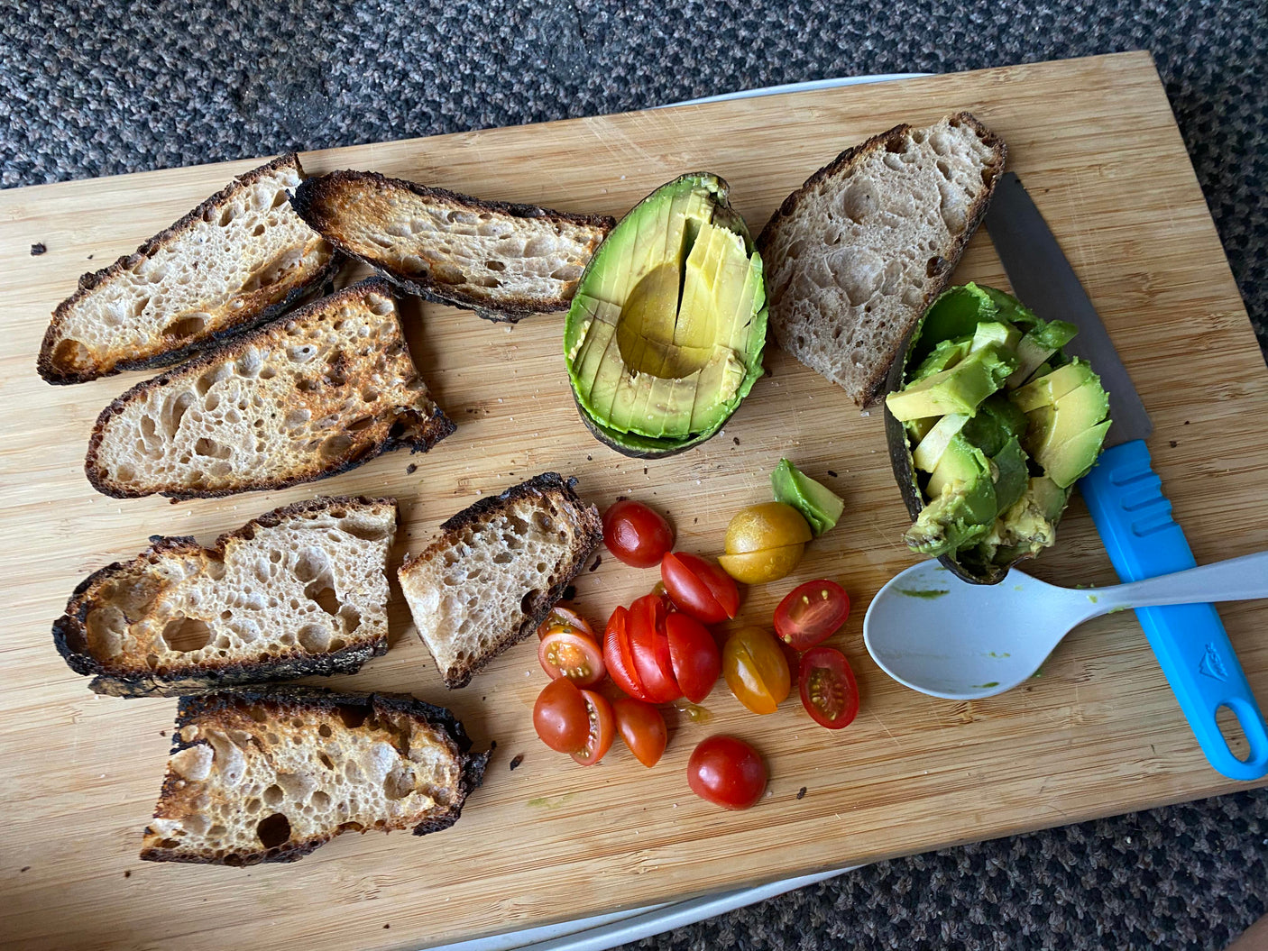 Preparing fresh avocado toast ingredients – charred bread, sliced avocado, and tomatoes on a cutting board – ideal for an RV rental.