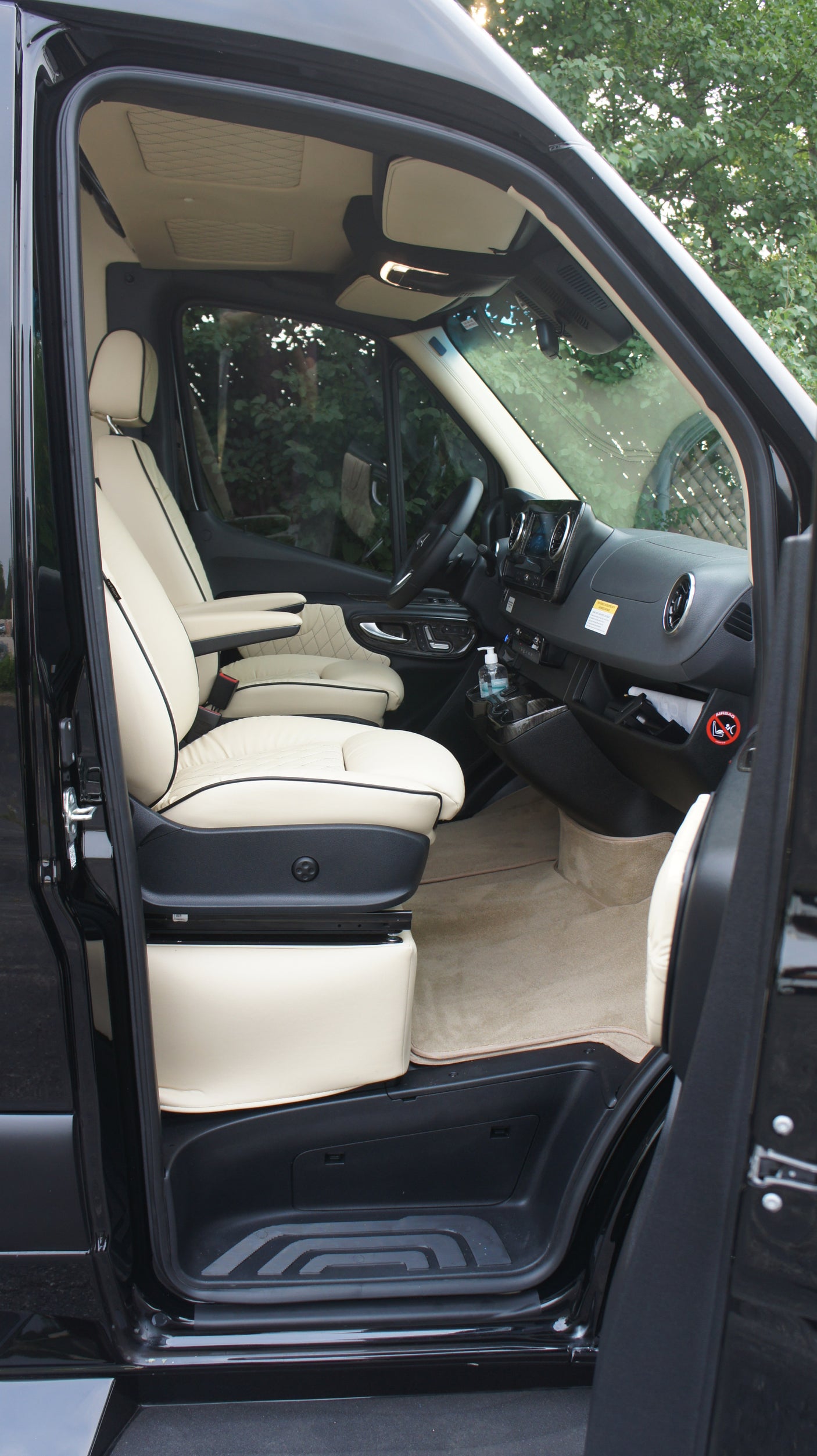 Black luxury van's creamy custom interior: swiveling driver's seat, modern dash. Ideal for RV rental adventures.