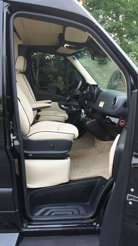 Black luxury van's creamy custom interior: swiveling driver's seat, modern dash. Ideal for RV rental adventures.