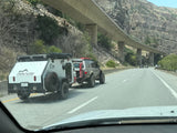 Adventure-ready RV rental setup: An off-road SUV tows a Venture Overland camper through scenic mountains.