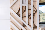 An RV rental's unique wall: white crisscross slats over natural wood slices. A window and control panel are visible.