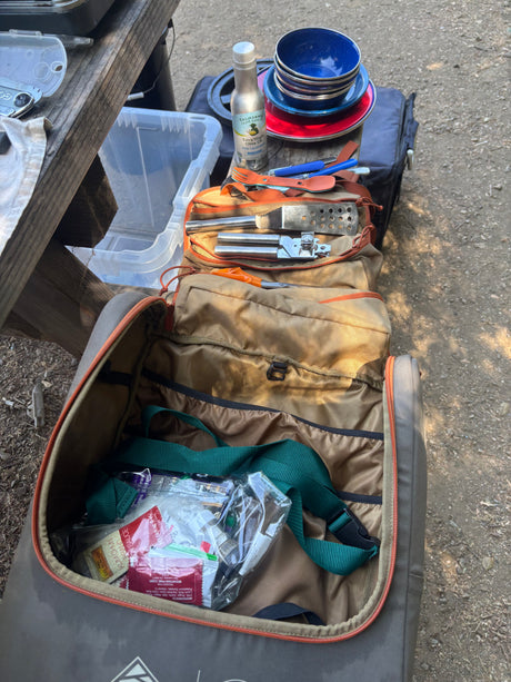 RV rental kitchen essentials: plates, olive oil, cooking tools, and sauces neatly packed in a travel bag for camping.