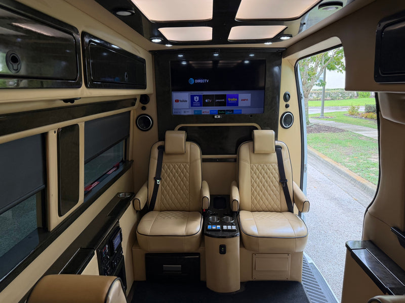 Luxury RV rental interior: two tan leather seats, large screen TV with DIRECTV & apps, comfort controls. Ideal for travel. — photo 11