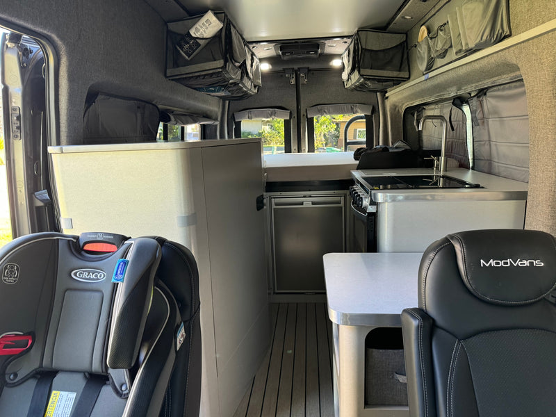  is parked on a sunny day with scenic views.|Gray ModVans Ford Transit campervan from side-rear view for rv rental — photo 15