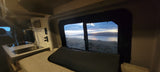 Enjoy tranquil lake views from this cozy RV rental's bed and kitchenette, offering a perfect setting for scenic road trips.