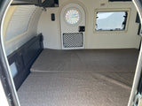 Cozy rv rental interior with gray bed, round door, and windows. Perfect for compact travel adventures.
