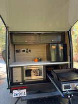 This RV rental offers a compact outdoor kitchen with a microwave, mini-fridge, and pull-out Blackstone griddle for camping meals.