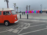 Enjoying Pismo Beach in a classic orange RV rental, with a thumbs-up from the driver and the colorful "PISMO BEACH" sign.