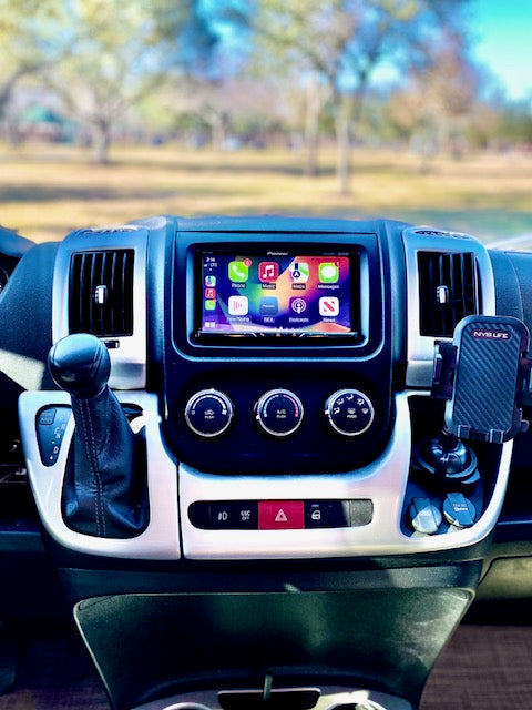 RV rental dashboard showing infotainment system with Apple CarPlay apps, climate controls, gear shifter, and phone mount.