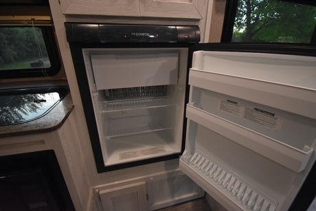 Clean, empty Dometic RV refrigerator with open door, showing shelves and freezer, in an RV rental.