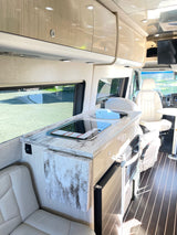 Bright RV rental interior with compact kitchen, light wood cabinets, and comfortable seating.