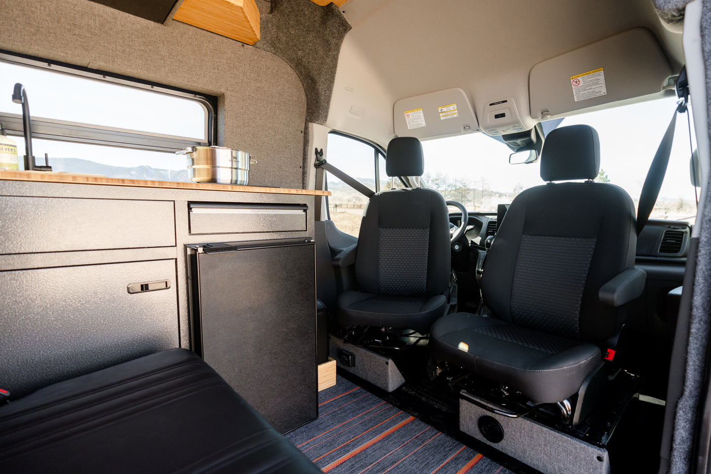 Spacious camper van interior featuring a kitchen with sink, fridge, and front cabin seats. Perfect for your next rv rental adventure.