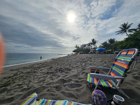 Sunny black sand beach day. Colorful chair by the ocean, a perfect stop during an RV rental trip.