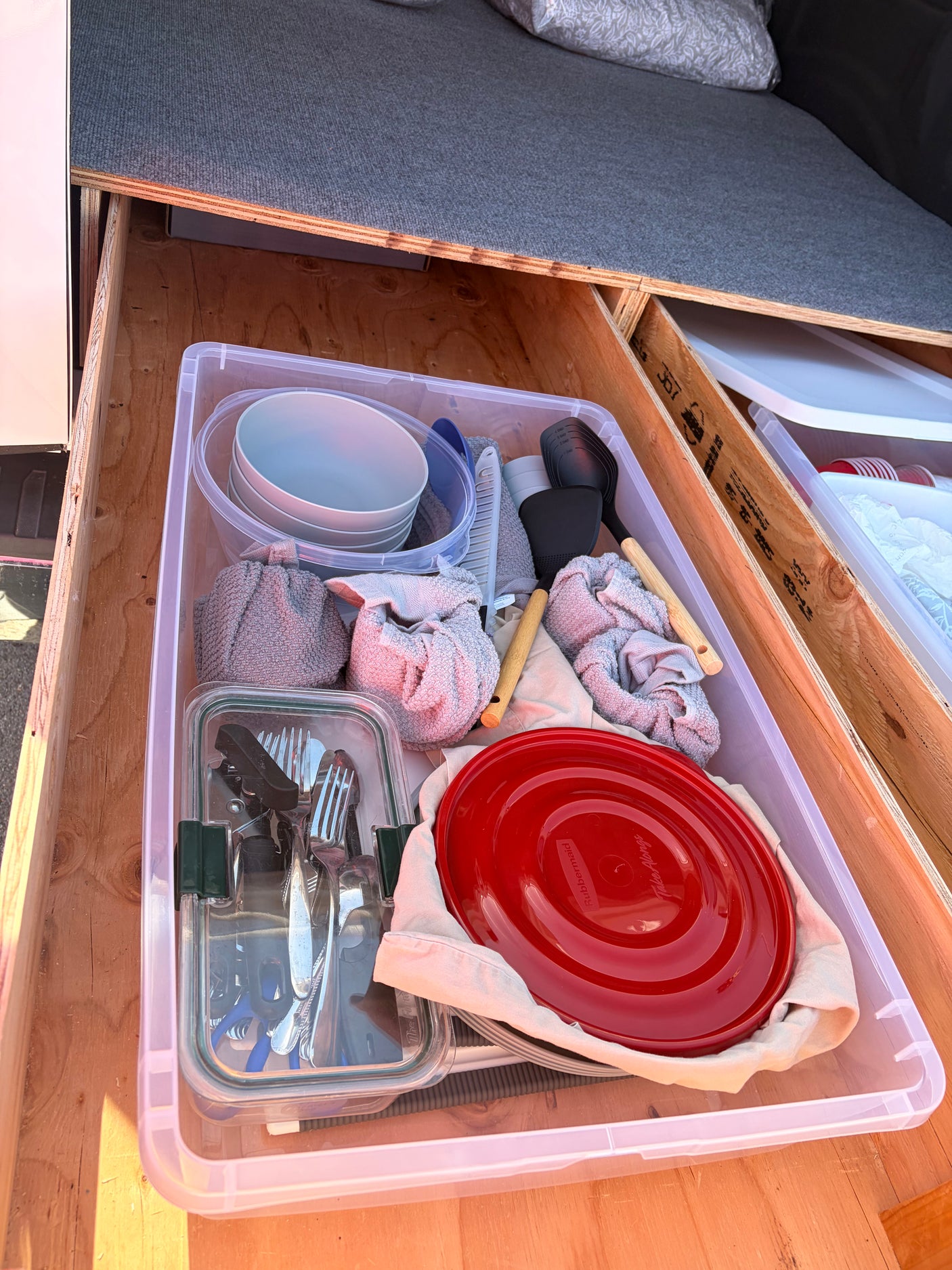 RV rental kitchen drawer stocked with camping kitchenware: plates, utensils, towels, and cooking tools neatly organized.