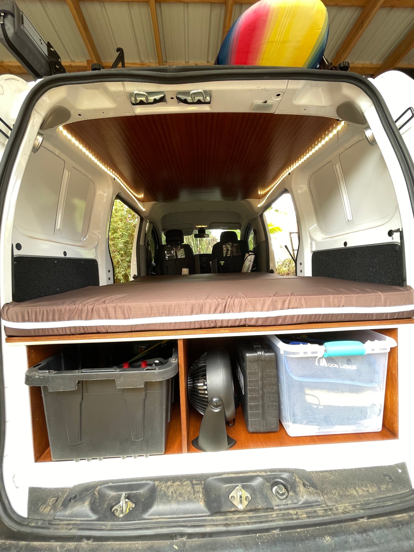 Spacious and organized camper van interior, perfect for RV rental adventures. Features a cozy bed, ample storage, and LED lighting.