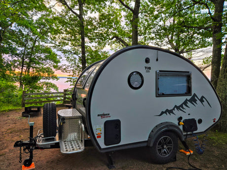 This T@B teardrop RV rental offers stunning lakeside sunset views at a peaceful wooded campsite, perfect for outdoor travel.