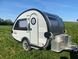 Explore the outdoors with this teardrop nuCamp Boondock Lite **rv rental**, parked in a sunny, green field.