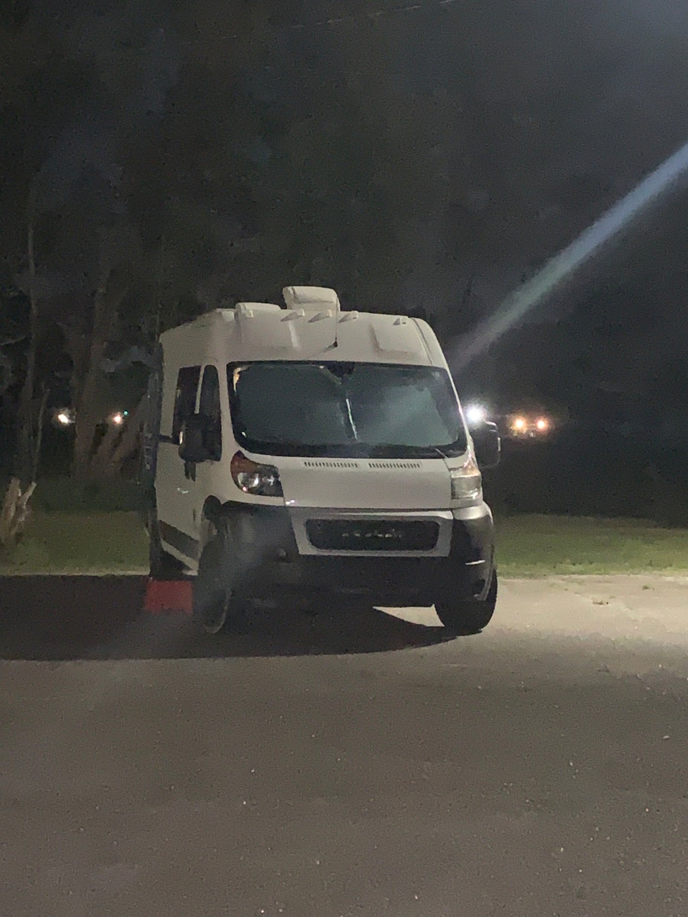 White camper van, resembling an RV rental, parked on asphalt at night.