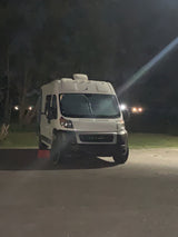 White camper van, resembling an RV rental, parked on asphalt at night.