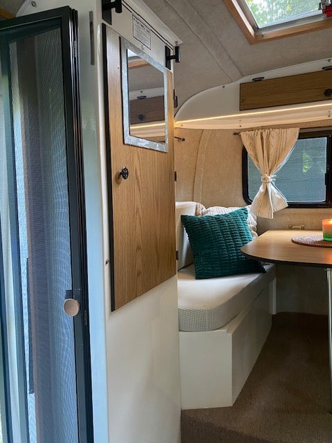 Experience a cozy **RV rental**: compact interior with bench seating, a small table, and a screen door for ventilation. — photo 7