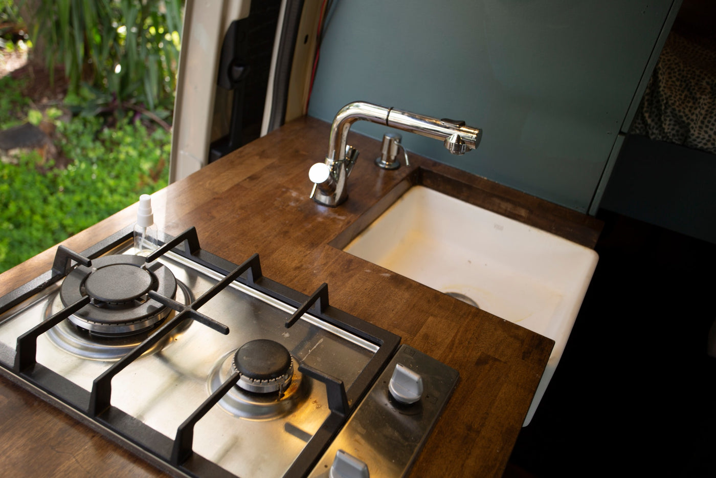 RV rental interior: practical kitchen with two-burner stove, sink, and wooden countertop for mobile cooking. — photo 5