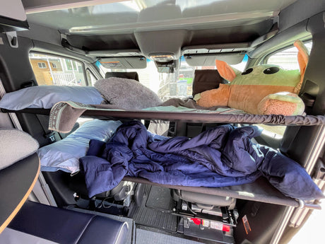 Cozy RV rental interior featuring two bunk beds with bedding, including a Grogu plushie on the top bunk.