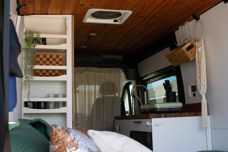 Step inside this RV rental! Cozy campervan living with a built-in kitchen, bed, and smart shelving for your adventures. — photo 7