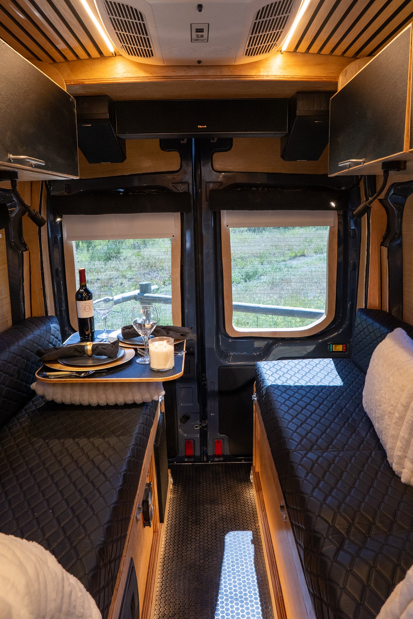 RV rental: Charming camper van interior with a dining table set for two, plush seating, and ambient lighting.