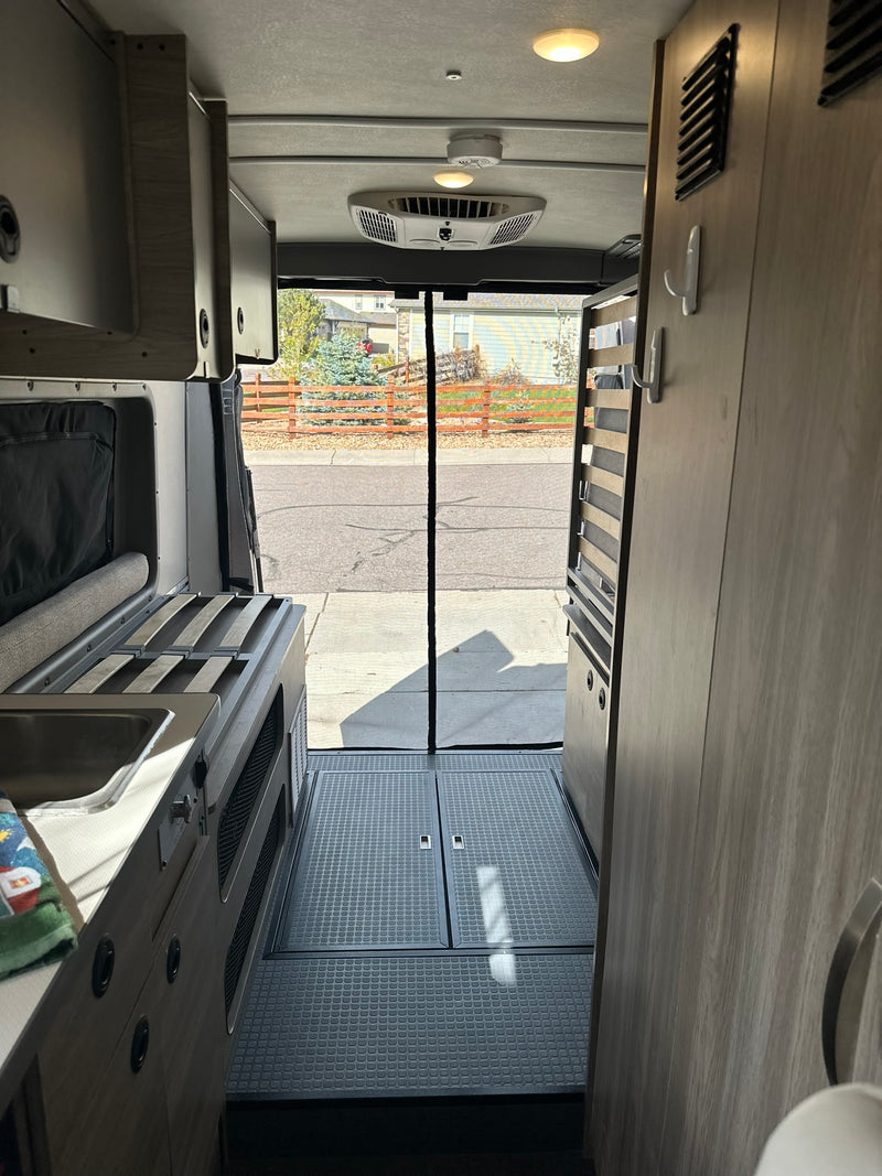 Step inside this RV rental! View from the back of a camper van, featuring a kitchenette, storage, and an open street view. — photo 2
