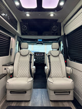 Luxurious RV rental interior featuring two light-colored captain's chairs, wood floor, and elegant modern amenities.
