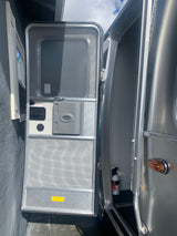 Open Airstream RV rental door, revealing screen, interior, and a fire extinguisher. Note "winterized" label.