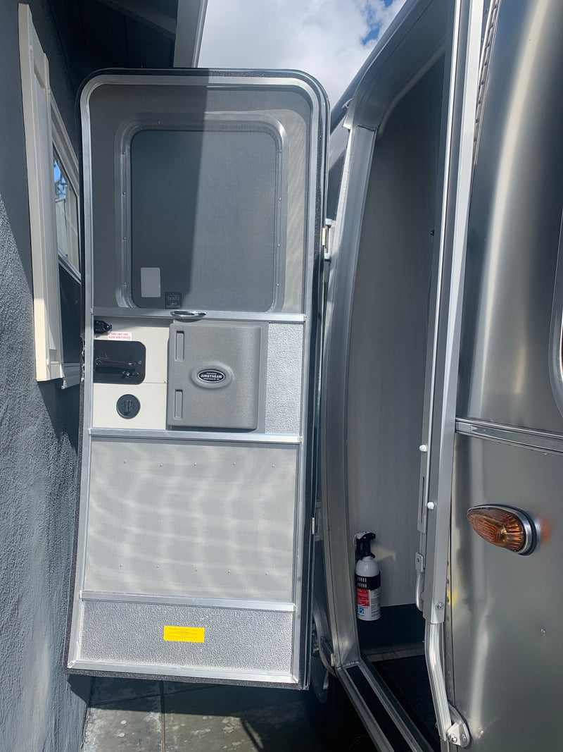 Open Airstream RV rental door, revealing screen, interior, and a fire extinguisher. Note "winterized" label. — photo 3