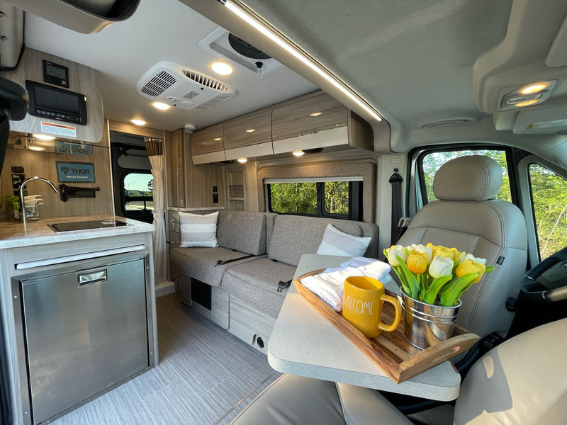 Modern RV rental interior, bright & comfortable with a kitchenette, sofa, and welcome tray, ready for travel. — photo 7