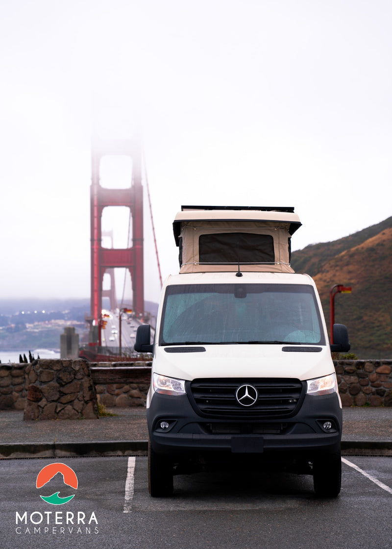  featuring a kitchen and pop-top roof near the beach.|White Mercedes Sprinter RV rental parked in front of a foggy Golden Gate Bridge — photo 6