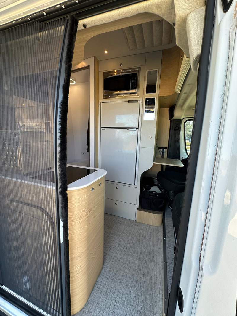 RV rental interior with modern kitchen, fridge, microwave, screen door, and compact desk. — photo 7