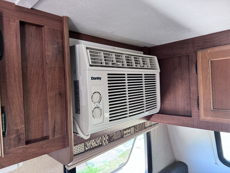 A compact Danby AC unit is built into the wooden overhead cabinets of an RV rental, providing essential cooling for your trip. — photo 8