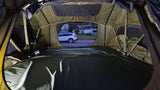Inside a spacious RV rental rooftop tent with a mattress, looking out at an SUV parked on a quiet street at dusk.