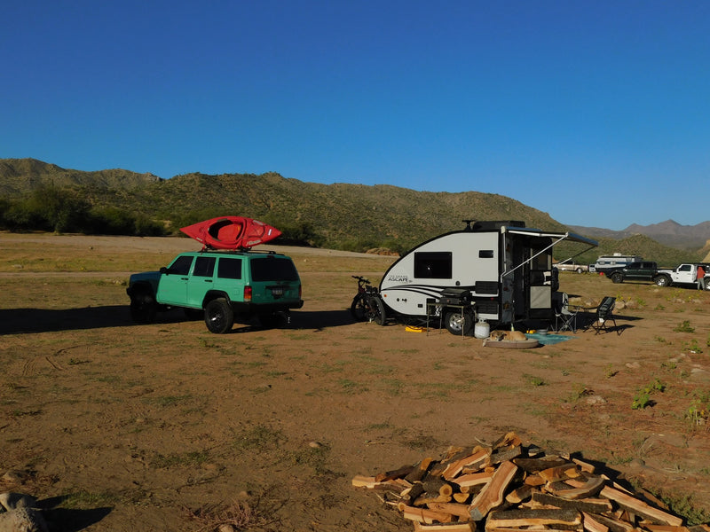 Teardrop RV rental camping with a kayak-equipped Jeep, dog, and firewood in a scenic desert landscape. — photo 9