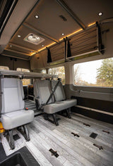 Spacious RV rental interior with modular seating, an adjustable bed system, and overhead storage for flexible travel.