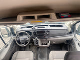 Inside an RV rental van: Ford dashboard, steering wheel, gear shift, and overhead storage with a visible first aid kit.