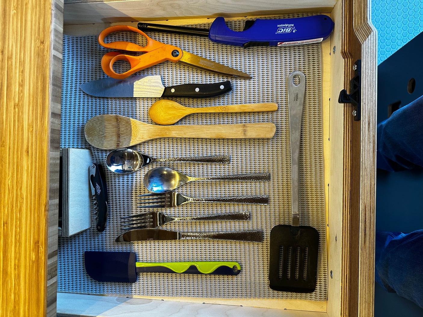 RV rental kitchen drawer neatly holds essentials: knife, scissors, wood spoons, metal cutlery, spatula, and a lighter.