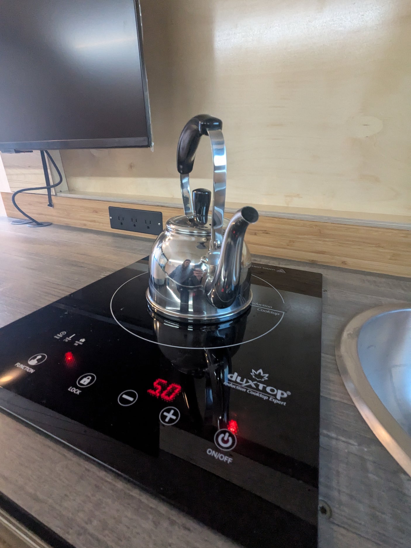 Inside an RV rental: a gleaming kettle sits on a DuxTop induction cooktop, powered on for quick hot water in this compact kitchen.