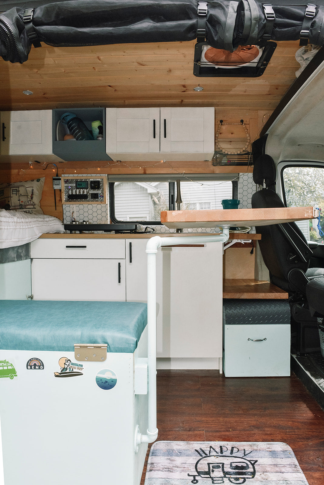 Explore this RV rental's clever interior: a wood-paneled kitchen, comfy bench, smart storage, and control panel.