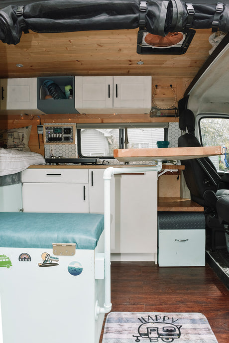 Explore this RV rental's clever interior: a wood-paneled kitchen, comfy bench, smart storage, and control panel.