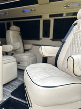 Luxury RV rental interior: cream quilted leather seats with armrests and blue overhead lighting for premium travel.