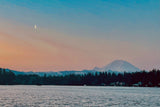 Crescent moon over a tranquil lake with Mount Rainier and forest at dusk. Plan your scenic RV rental escape.