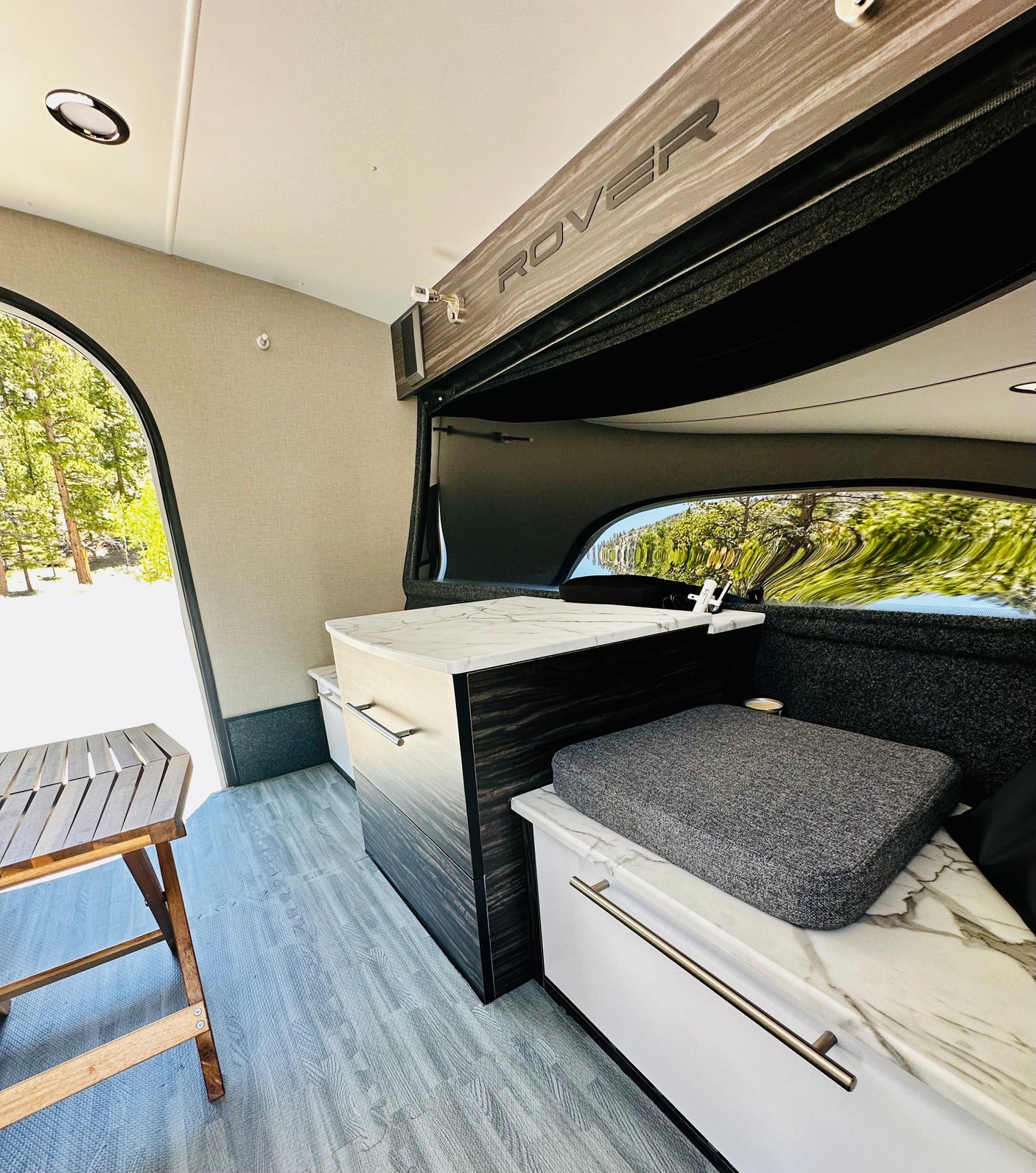 Stylish RV rental interior: compact kitchen, cozy seating, and wide window view. Ideal for road trips!