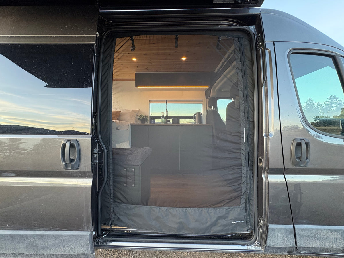 Open RV rental side door with a VanEssential screen, revealing a modern camper van interior, kitchen, bed, and wood ceiling. — photo 13