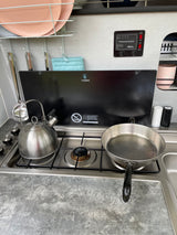Compact RV rental kitchen showing a Dometic stove, kettle, pan, and inTech Command Control panel for systems.