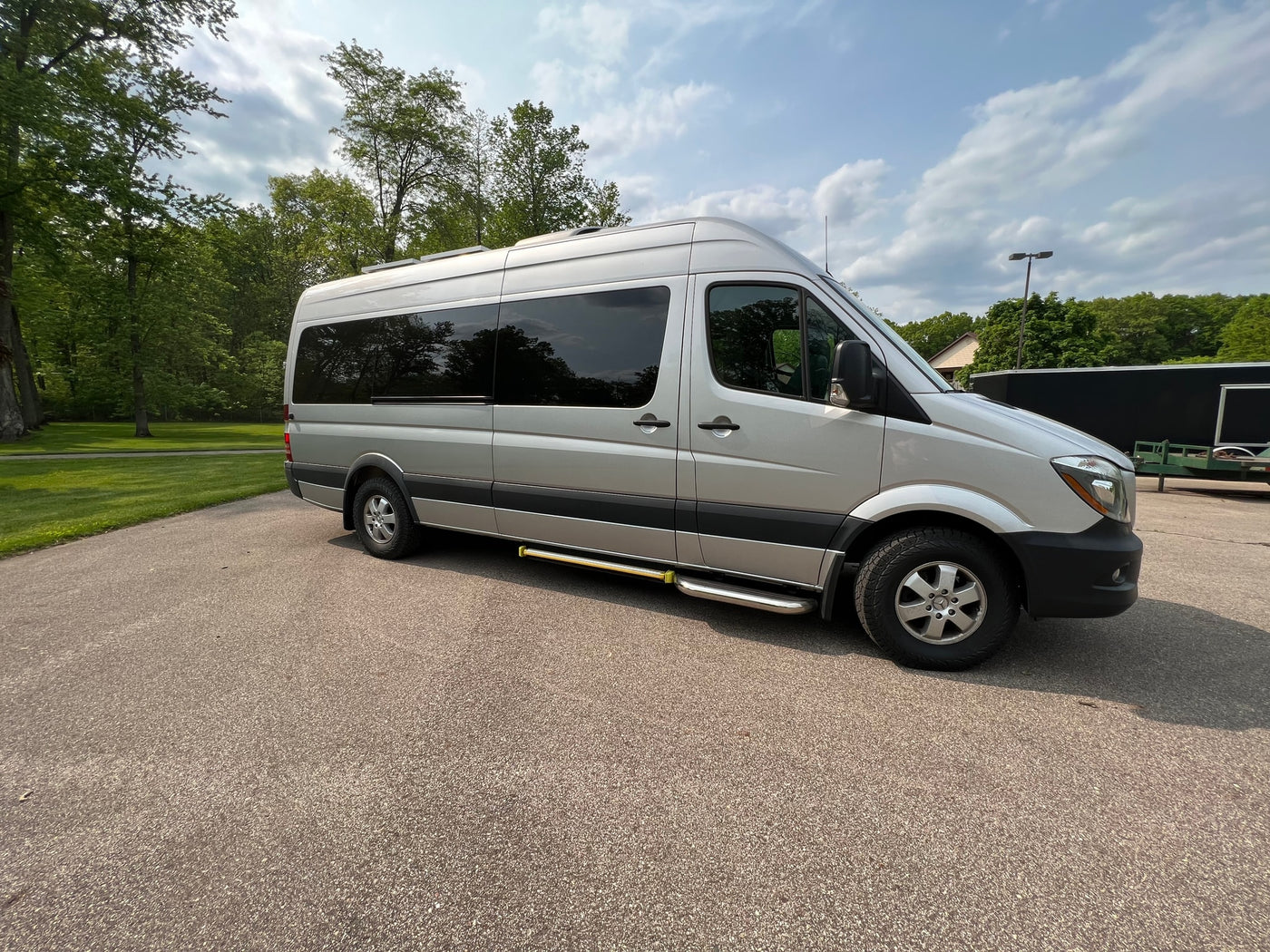 Silver Sprinter van, ideal for RV rental, parked on asphalt with trees and a cloudy sky. Perfect for an adventure. — photo 8